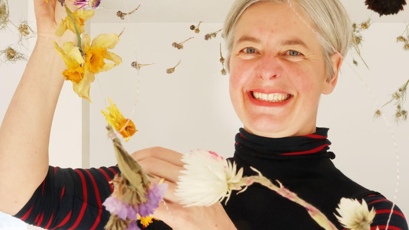 Umgeben von schwebenden Blüten arbeitet Sandra Ganser.