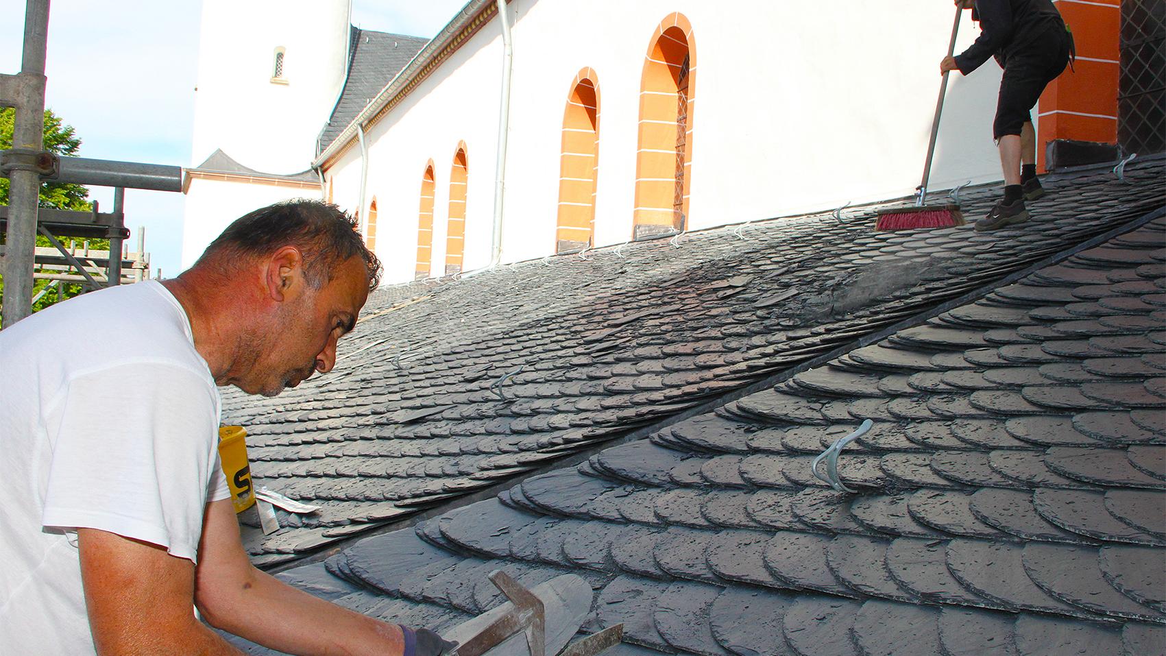 Gemäß „Altdeutscher Deckung“ ein Dach zu beschiefern, das kann nicht jeder Dachdecker. Geselle Ergin Birihci (vorne) weiß, wie es geht. Gesellenkollege Heinz Beyer fegt das Dach. (c) Stefan Lieser