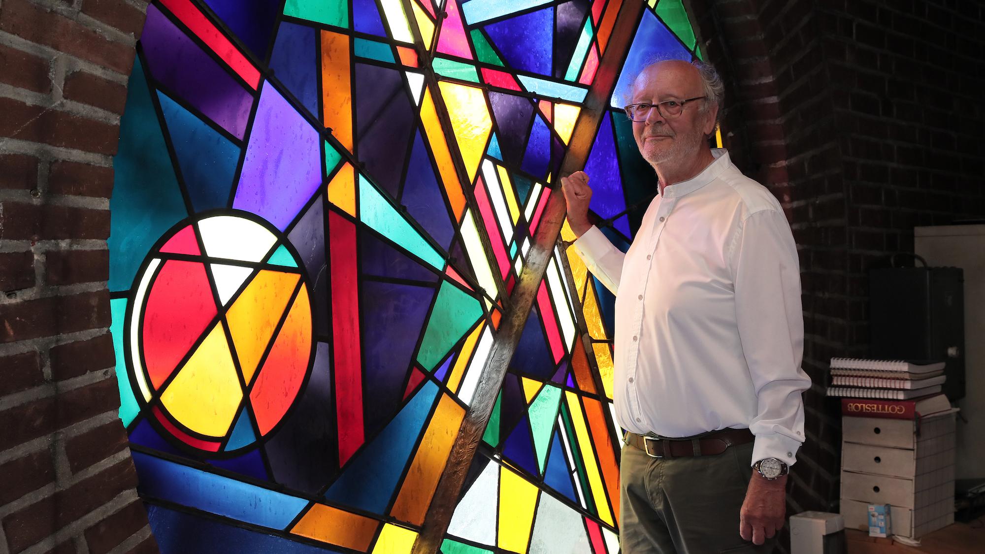 Hans Riskes, stellvertretender  Kirchenvorstand, vor dem von Joachim Klos gestalteten Kirchenfenster über der Orgelempore. (c) Dirk Jochmann