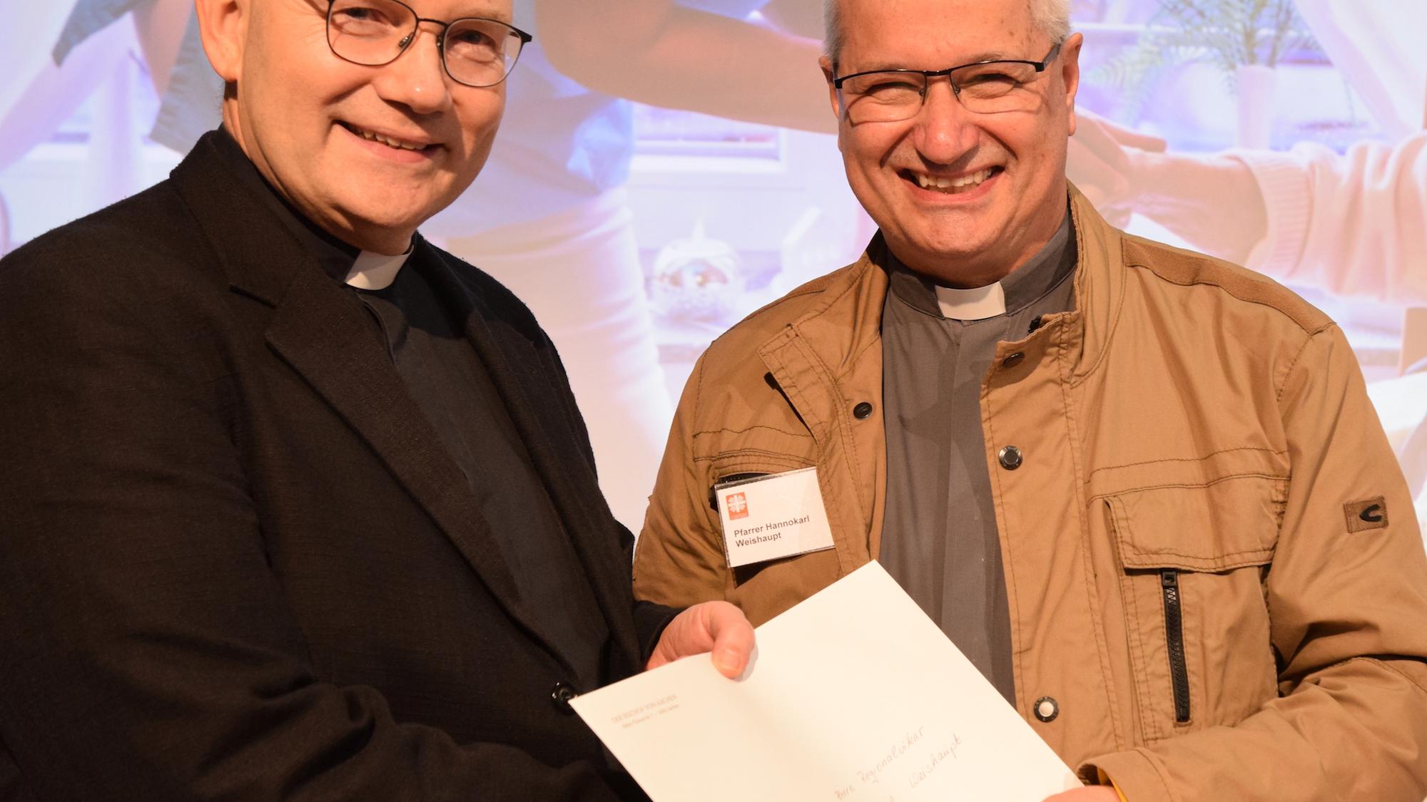 Regionalvikar Hannokarl Weishaupt (r.) erhält die Ernennungsurkunde zum Bischofsvikar für das Caritaswesen aus der Hand Bischof Helmut Diesers. (c) Thomas Hohenschue