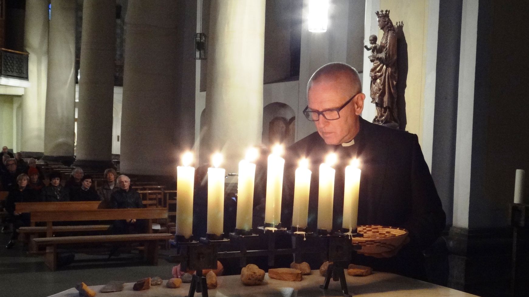 Pfarrer Rainer Gattys legt in Erinnerung an die Würselener Juden Steine auf den Altar. (c) Vladimir Shvemmer