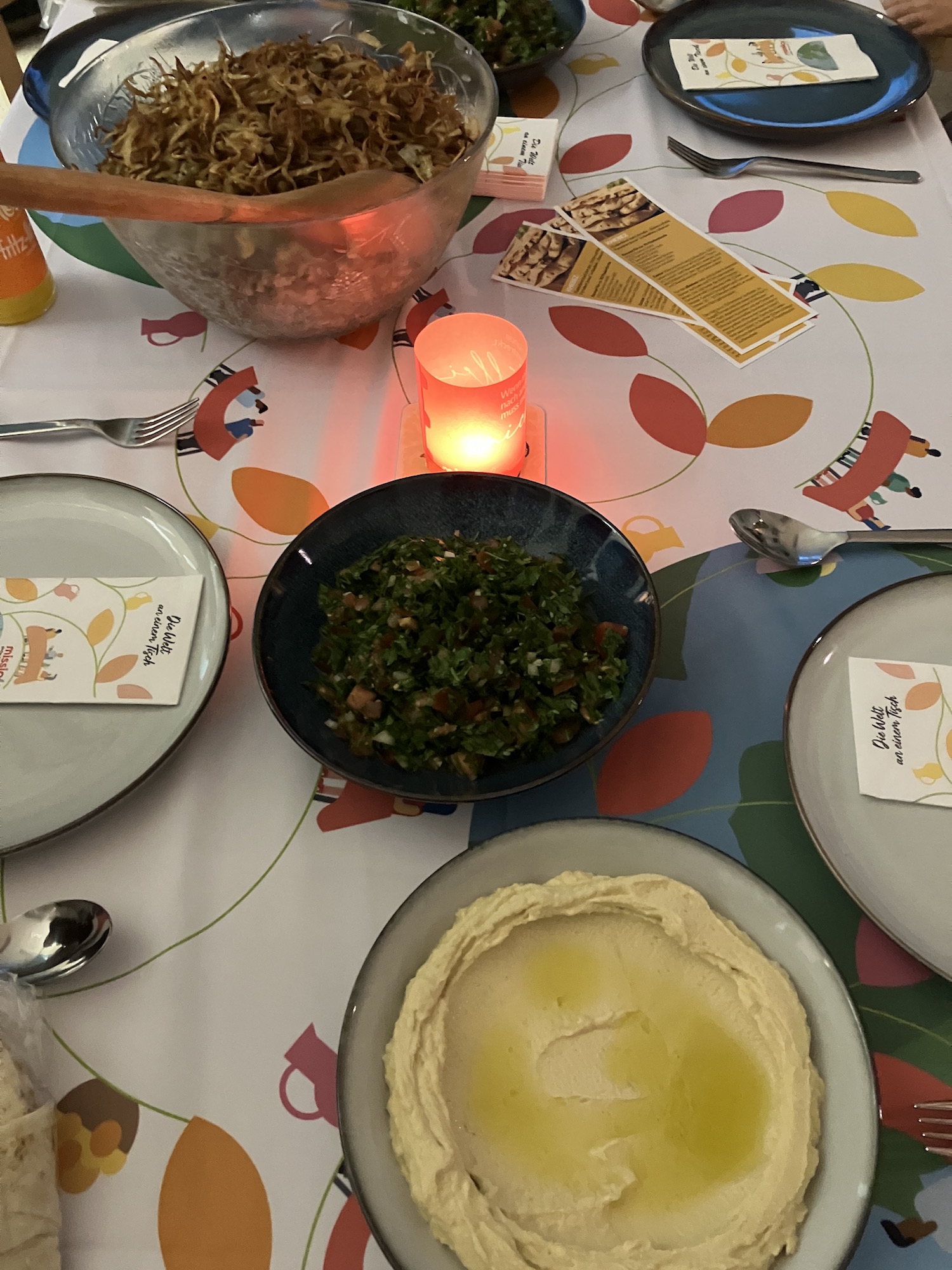 · Bei Humus, Tabouleh und Linsen mit Zwiebeln und Reis versammeln sich Gäste, Gemeindemitglieder und Missio-Mitarbeiter um einen Tisch. (c) Andrea Thomas