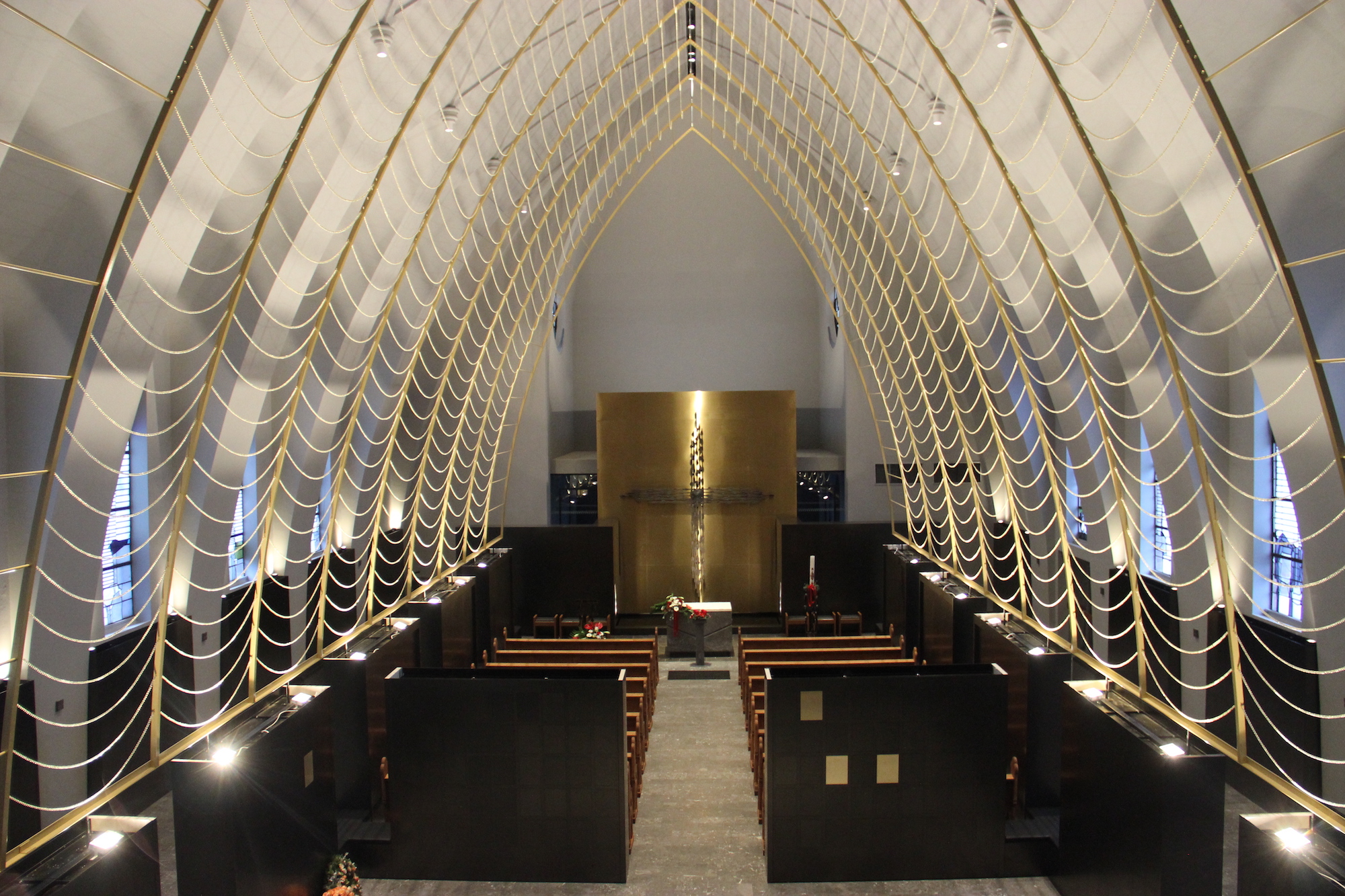 Wie ein Netz aus Licht spannen sich von unten angestrahlte Messingketten über die Kapelle.