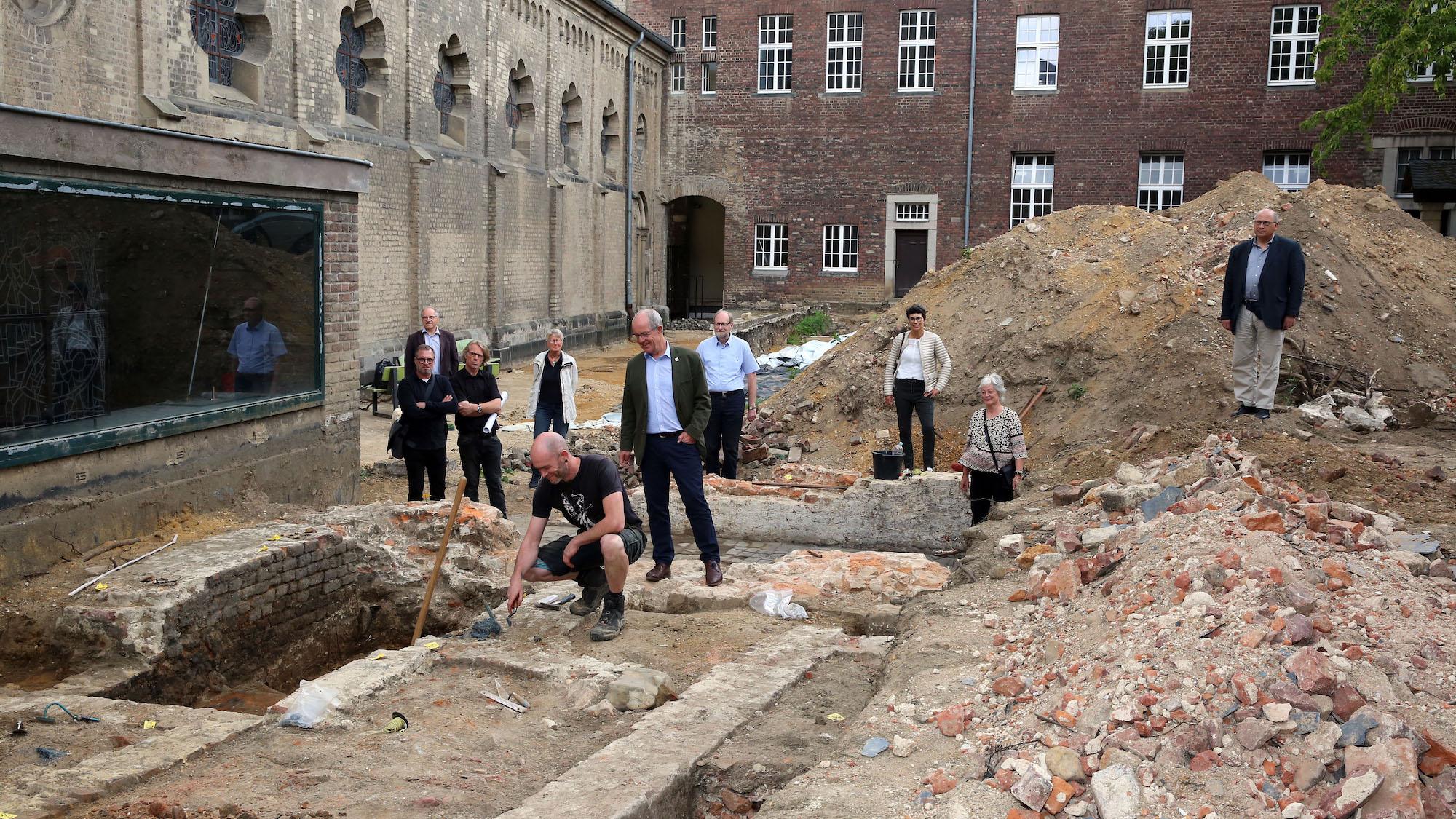 Archäologe Dáire Leahy (vorne, hockend) zeigt die freigelegten Fundamente des früheren Kreuzgangs der Abtei. (c) Stadt Mönchengladbach