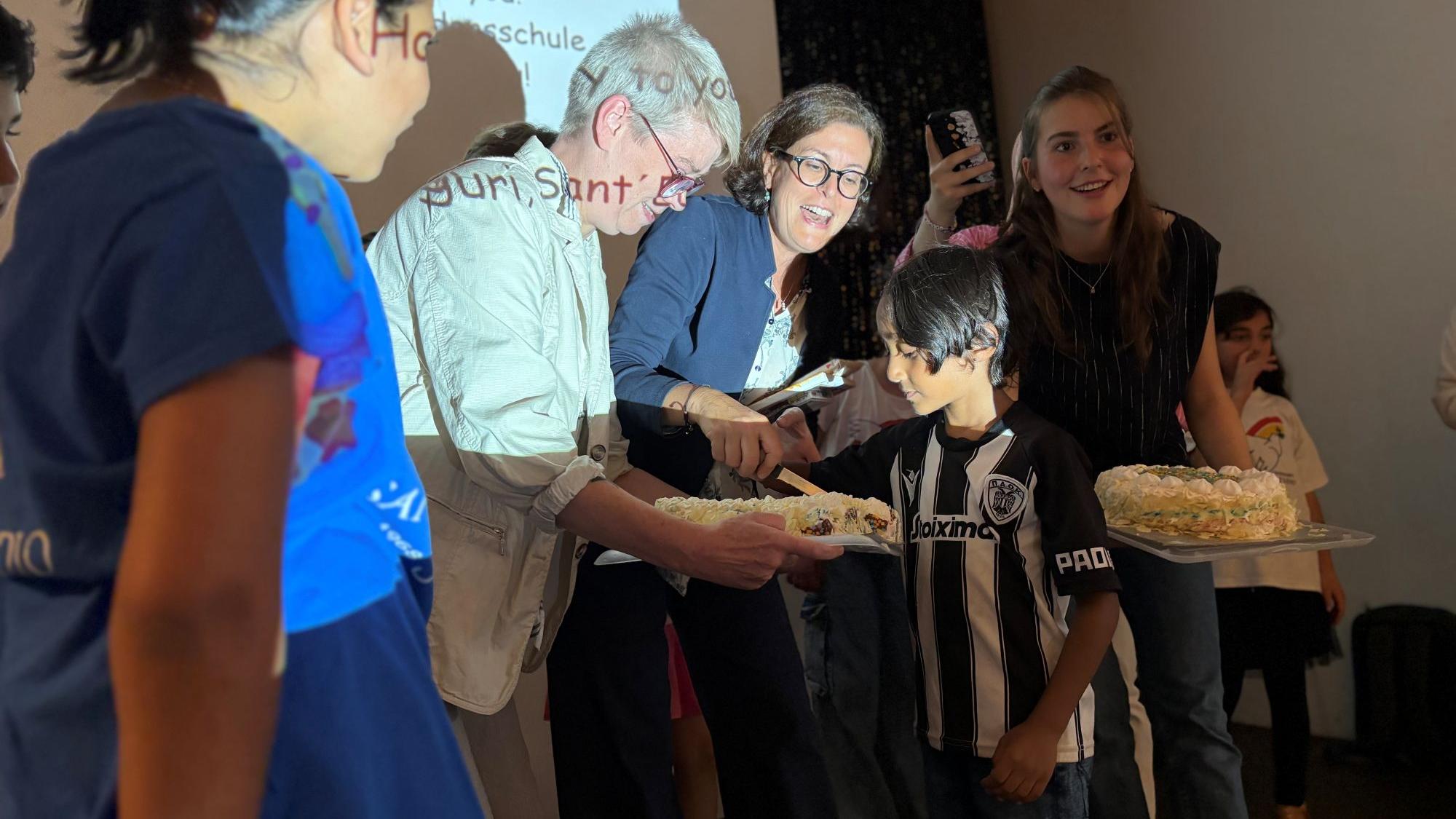 Nicole „Nicki“ Waur (l.) und Argiris (6) schneiden die Geburtstagstorte an. (c) Garnet Manecke