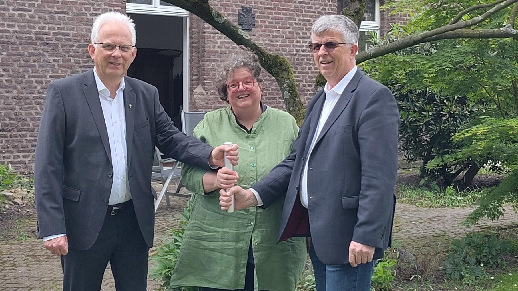 Als Team in der Region unterwegs: Propst Thomas Eicker (l.), Gabi Terhorst und Harald Hüller. Symbolisch teilen sie sich einen Staffelstab. (c) Kathrin Albrecht