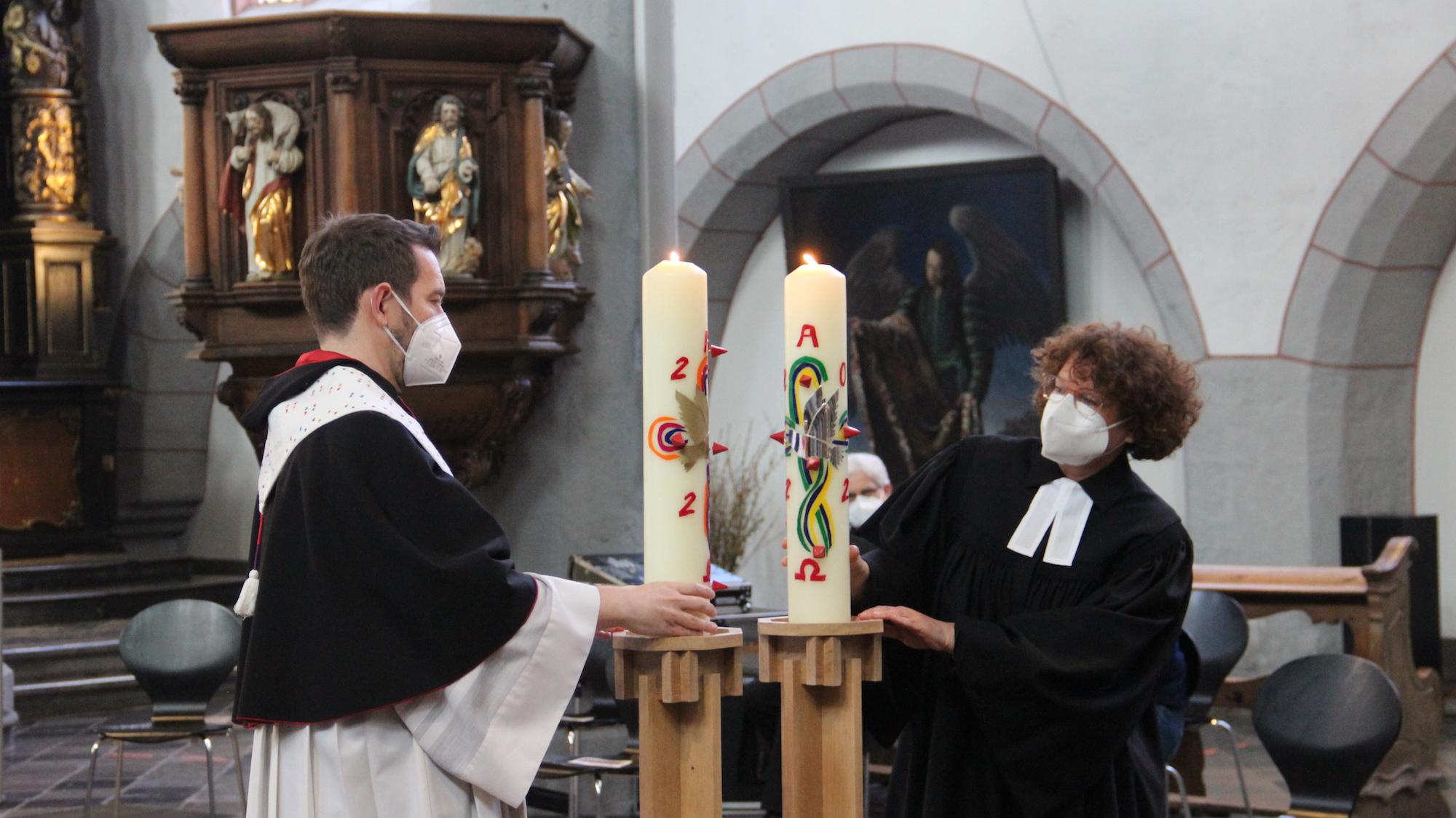 Pfarrer Matthias Fritz (KHG) und Pfarrerin Swantje Eibach-Danzeglocke (EHG) setzen die Kerzen auf die neuen Leuchter. (c) Andrea Thomas