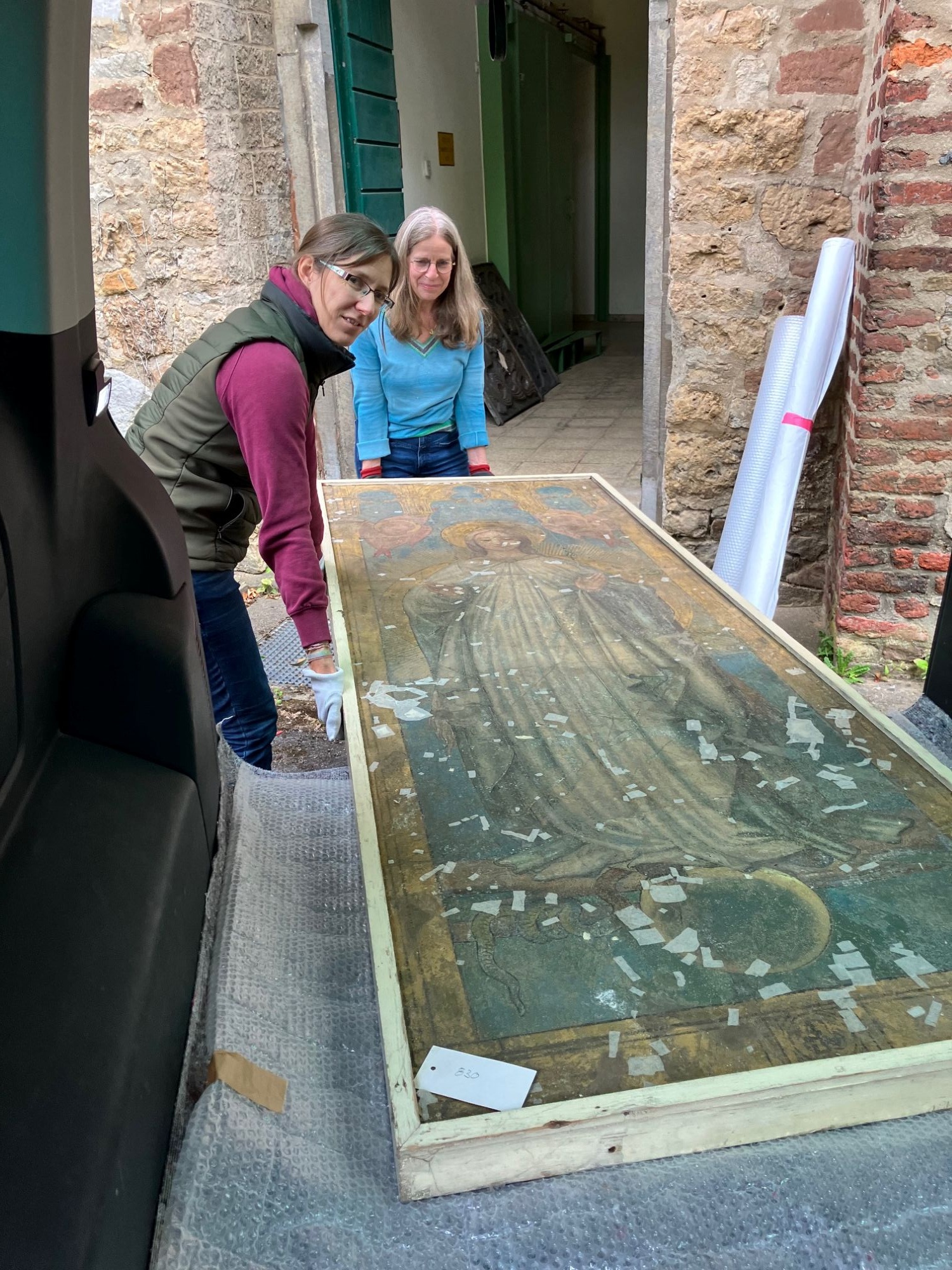 Anna Welding und Karen Keller begleiten das noch unrestaurierte Bild in den Transporter. (c) Bistum Aachen/Andreas Steindl