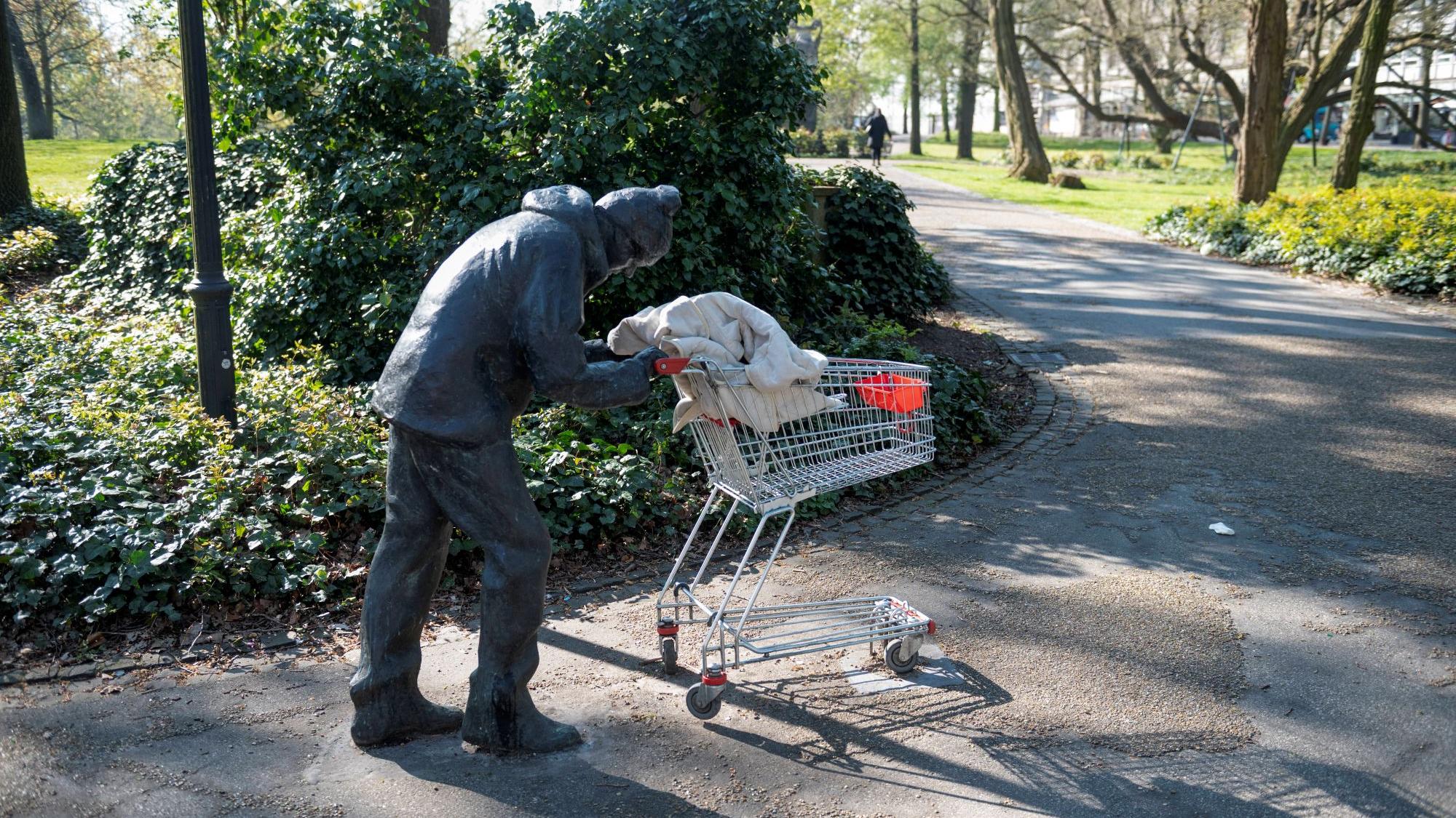 2020 stand die Bronzestatue eines gebeugten Mannes, der seine Habseligkeiten im Einkaufswagen vor sich herschiebt, plötzlich in den Bremer Wallanlagen. Das Werk stammt von einem unbekannten Künstler, der sich auf Instagram „Mohamed Smith“ nennt. (c) Imago/ Richard Wareham